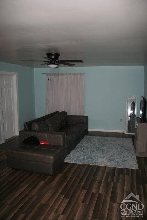 living room featuring ceiling fan and dark wood-type flooring