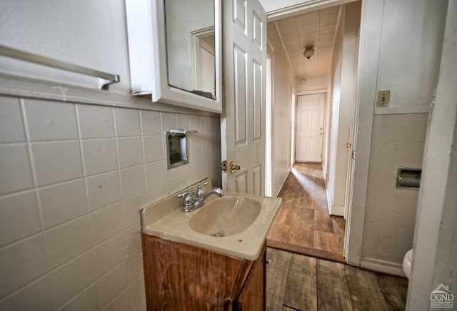 bathroom with hardwood / wood-style floors, vanity, toilet, tile walls, and tasteful backsplash