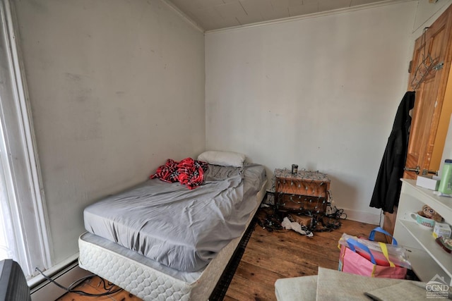 bedroom with hardwood / wood-style flooring, a baseboard radiator, and crown molding