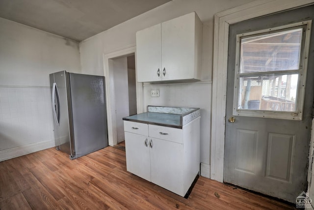 kitchen with white cabinets, hardwood / wood-style floors, and stainless steel refrigerator