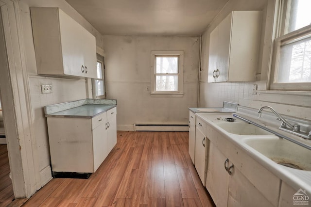 kitchen with white cabinets, a baseboard radiator, tile walls, and light hardwood / wood-style floors