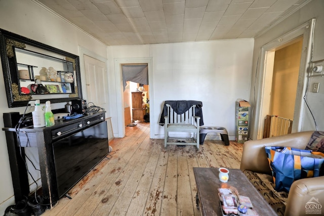 sitting room with crown molding and light hardwood / wood-style floors