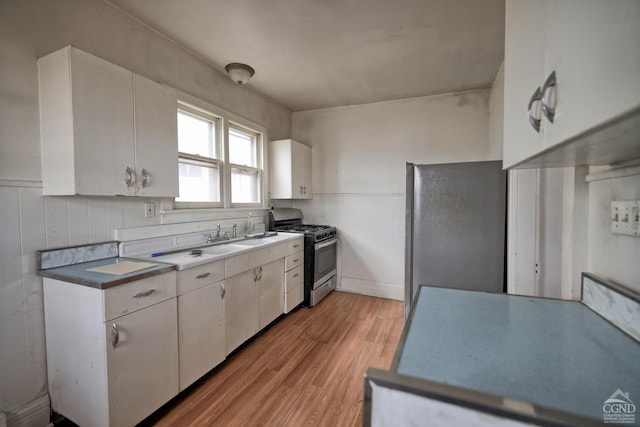 kitchen with white cabinets, tile walls, appliances with stainless steel finishes, and light hardwood / wood-style flooring