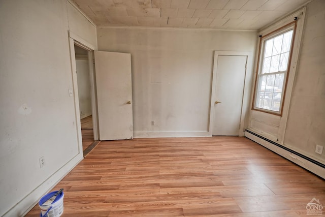 unfurnished room with a baseboard heating unit and light wood-type flooring