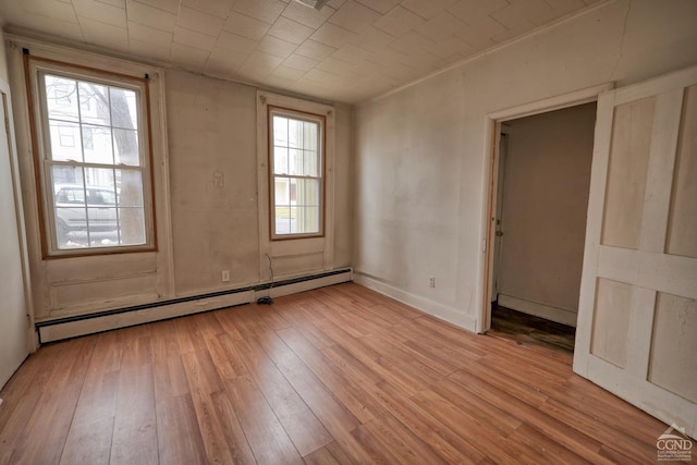 empty room featuring a baseboard radiator and light hardwood / wood-style floors