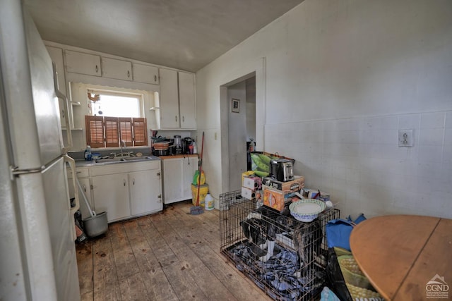 kitchen featuring light wood-type flooring, white fridge, white cabinetry, and sink