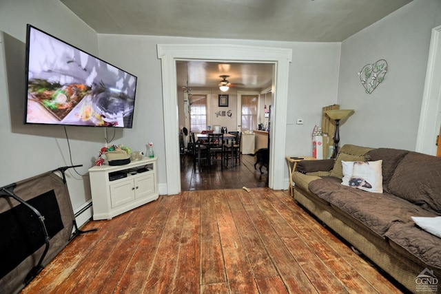 living room featuring baseboard heating, ceiling fan, and dark hardwood / wood-style floors