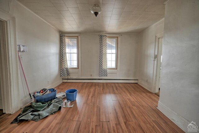 unfurnished room featuring light hardwood / wood-style floors, crown molding, and a baseboard radiator