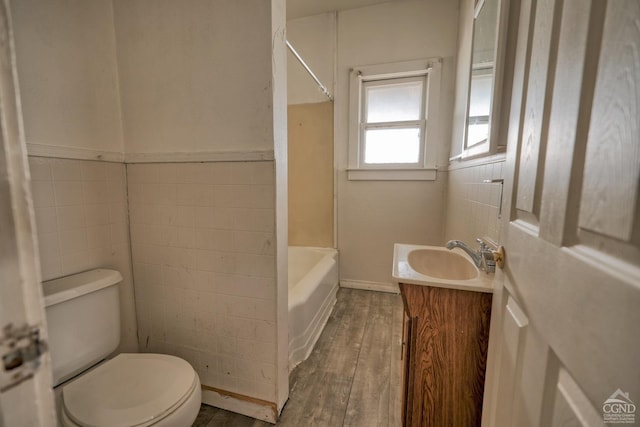 full bathroom featuring vanity, hardwood / wood-style floors, toilet, shower / bathing tub combination, and tile walls