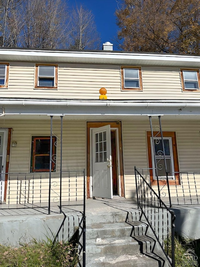 doorway to property featuring a chimney and a porch