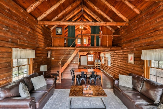 living room featuring a healthy amount of sunlight, log walls, beam ceiling, and wood ceiling