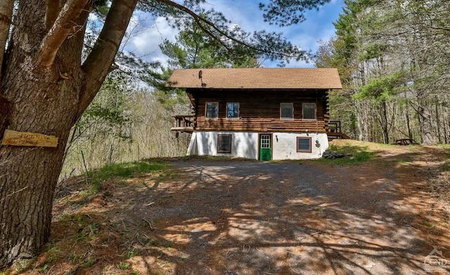 view of front of property featuring roof with shingles, log exterior, and a deck