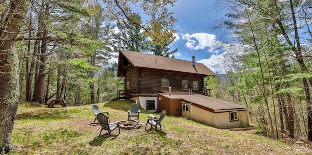 view of property exterior featuring an outdoor fire pit and log siding