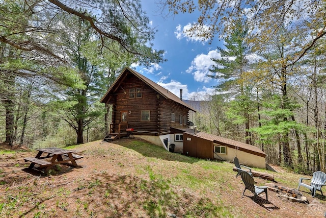 view of property exterior featuring log siding and an outdoor fire pit