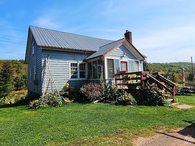 back of property featuring a deck, a sunroom, and a yard