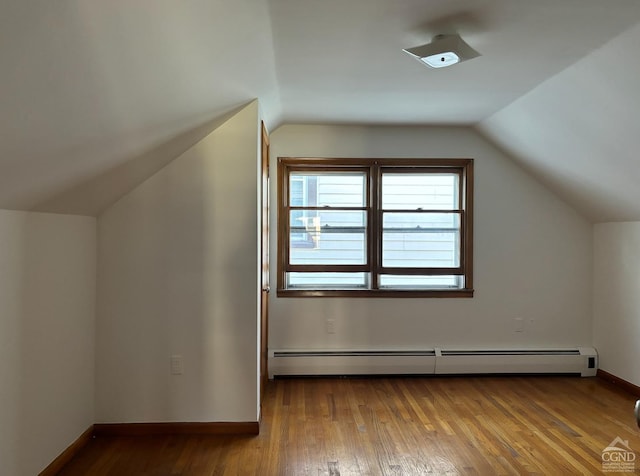 additional living space with hardwood / wood-style floors, baseboard heating, and vaulted ceiling