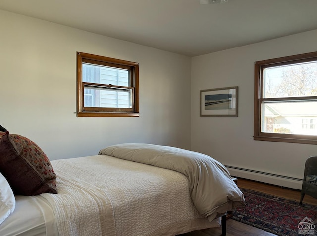 bedroom featuring hardwood / wood-style flooring, a baseboard radiator, and multiple windows