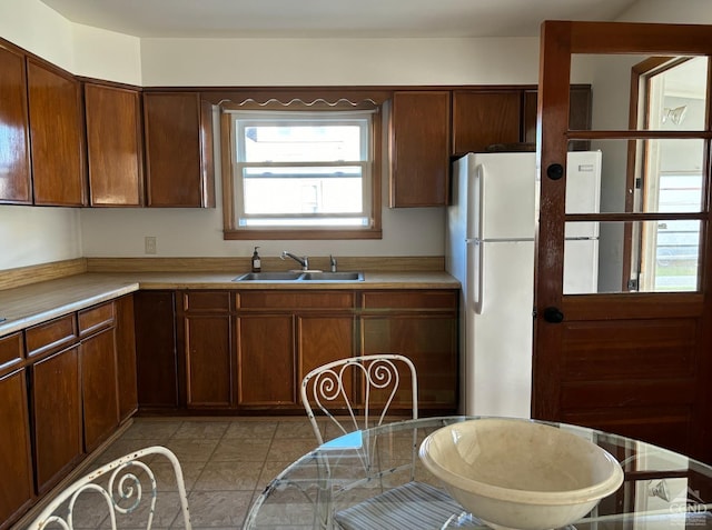 kitchen with sink, light tile patterned floors, and white fridge