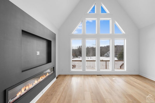 additional living space with high vaulted ceiling and light wood-type flooring