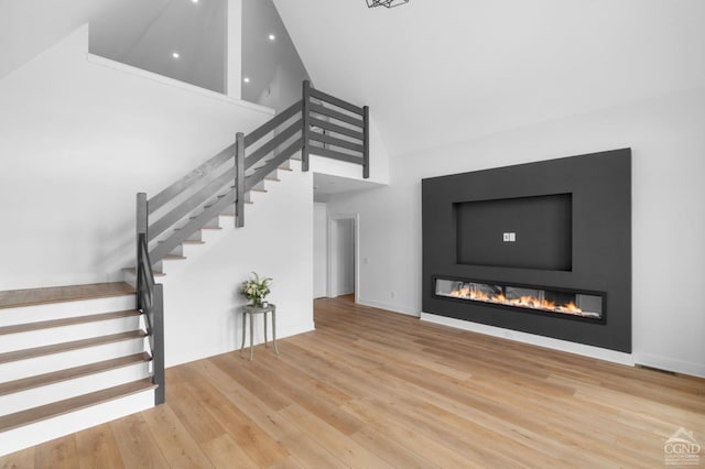 stairs featuring wood-type flooring and high vaulted ceiling