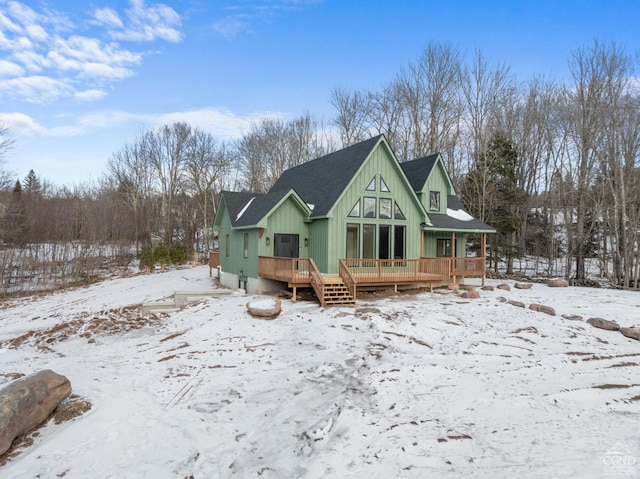 snow covered back of property featuring a deck