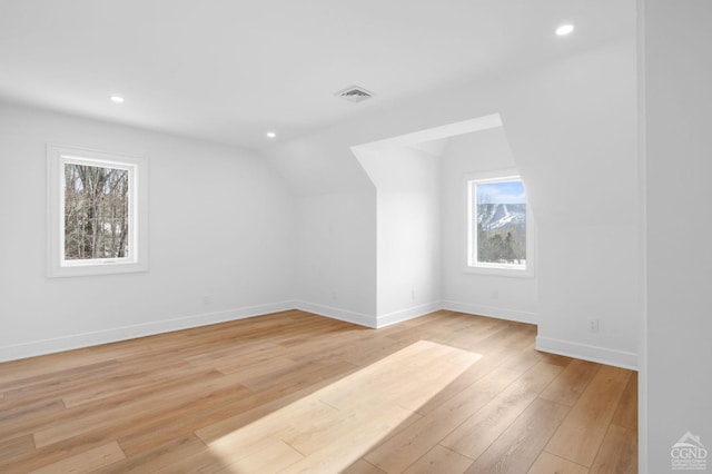 bonus room with vaulted ceiling, a healthy amount of sunlight, and light hardwood / wood-style floors