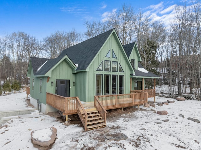 snow covered back of property featuring a wooden deck