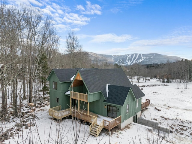 snow covered property with a deck with mountain view