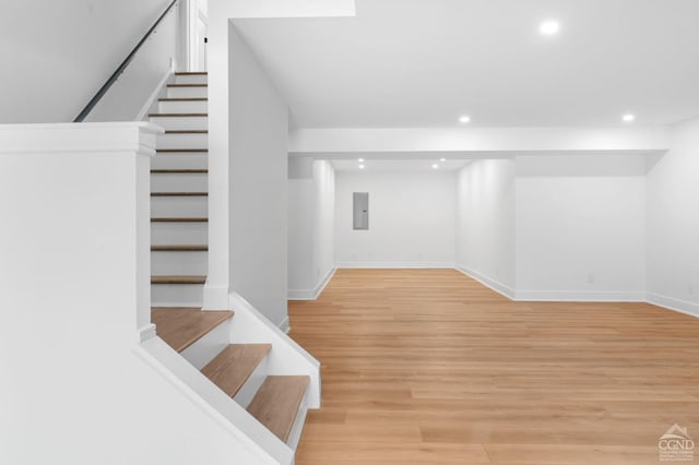 basement with light hardwood / wood-style floors and electric panel