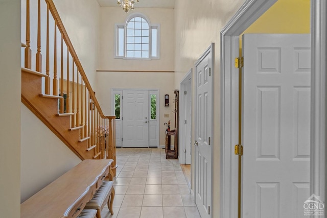 entrance foyer with a high ceiling, an inviting chandelier, and light tile patterned flooring