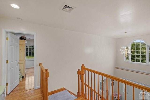 hall with an inviting chandelier and light hardwood / wood-style flooring