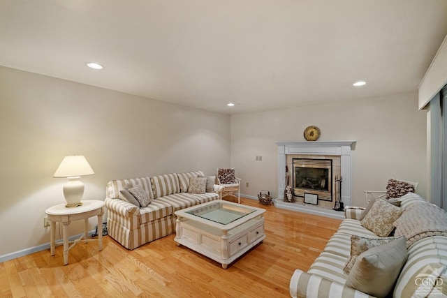 living room featuring a tiled fireplace and light wood-type flooring