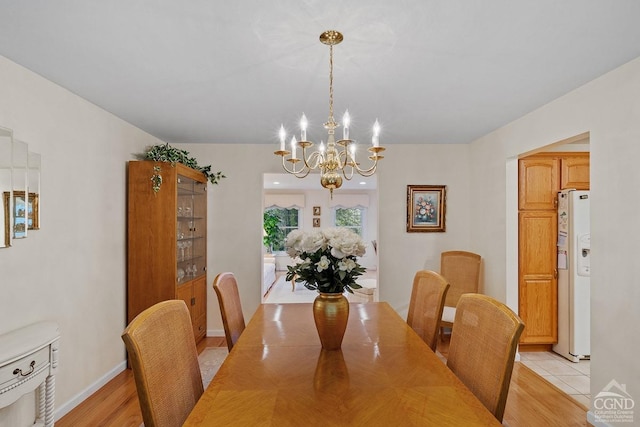 dining area with light wood-type flooring and a notable chandelier