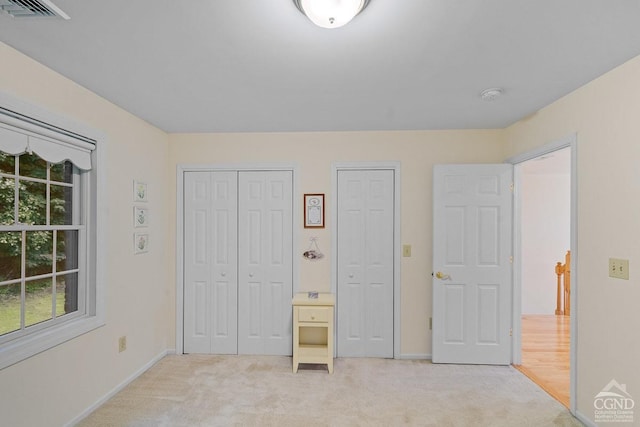 unfurnished bedroom featuring light colored carpet and two closets