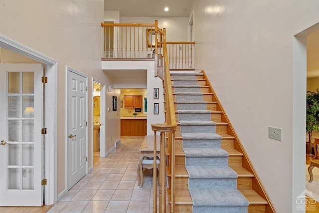 staircase featuring tile patterned flooring and a high ceiling