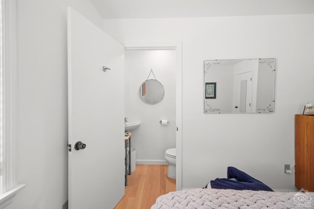 bathroom with toilet, wood finished floors, and baseboards