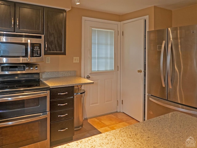 kitchen featuring appliances with stainless steel finishes, dark brown cabinetry, and light tile patterned floors