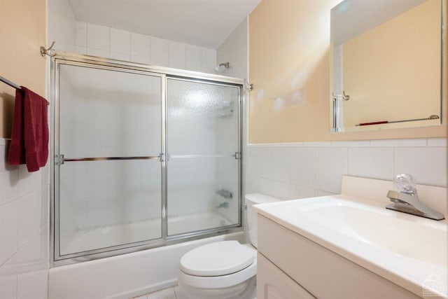 full bathroom with vanity, toilet, shower / bath combination with glass door, and tile walls