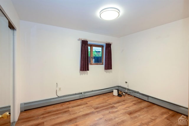 empty room featuring a baseboard radiator and light wood-type flooring