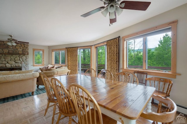 dining area with a fireplace, light parquet flooring, baseboard heating, and plenty of natural light