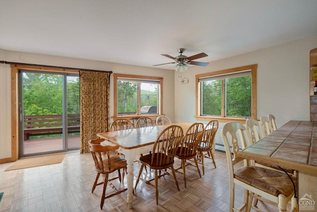 dining area with ceiling fan, light parquet flooring, and a baseboard heating unit