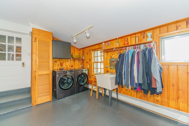 laundry area with a baseboard radiator, washer and clothes dryer, and wooden walls