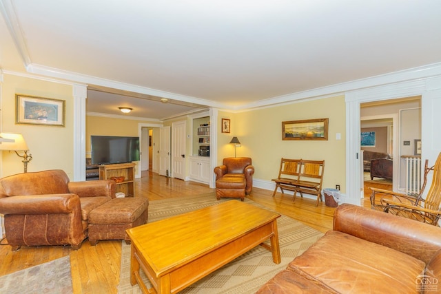 living room featuring hardwood / wood-style floors, decorative columns, and crown molding