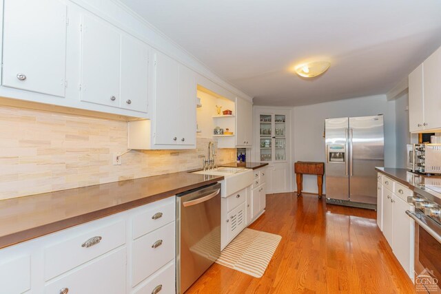 kitchen with white cabinetry, sink, stainless steel appliances, tasteful backsplash, and light hardwood / wood-style flooring