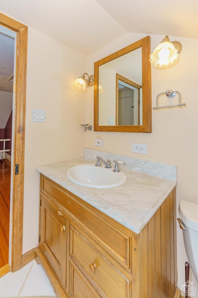 bathroom featuring tile patterned floors, vanity, toilet, and vaulted ceiling