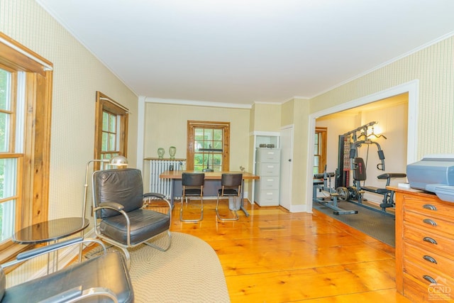 sitting room with light wood-type flooring and crown molding