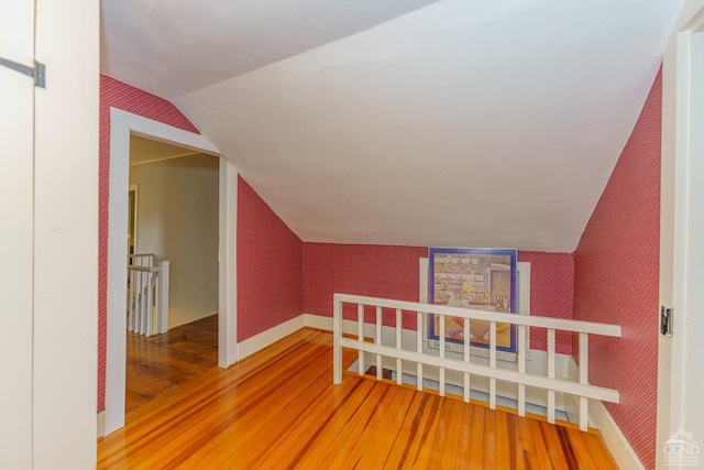 additional living space with hardwood / wood-style floors and vaulted ceiling