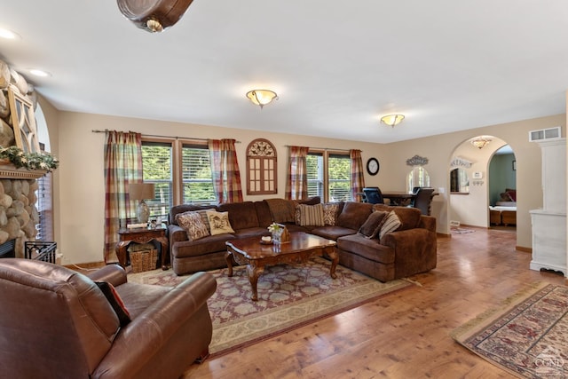 living room with a stone fireplace and wood-type flooring