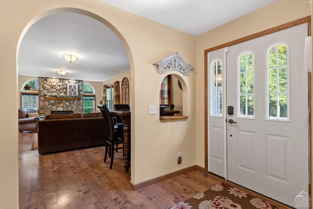 foyer entrance with hardwood / wood-style flooring and a stone fireplace