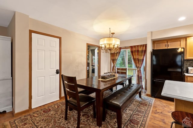 dining area with a notable chandelier and light hardwood / wood-style floors